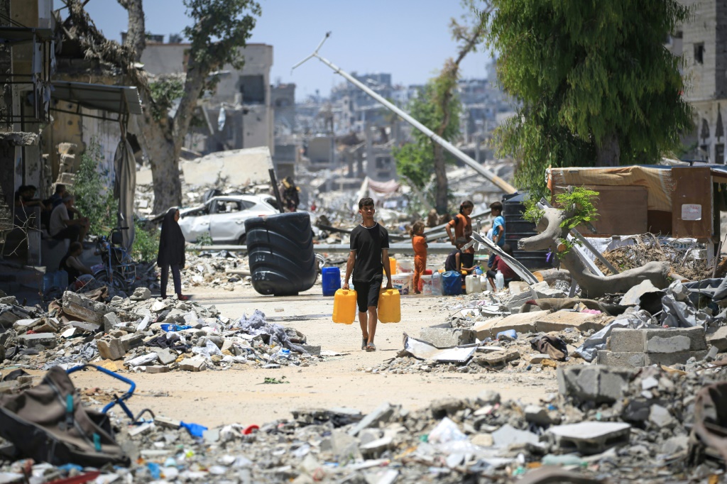 فلسطيني أمام بنايات مدمرة في خان يونس جنوب قطاع غزة في 11 حزيران/يونيو 2024 (أ ف ب)   