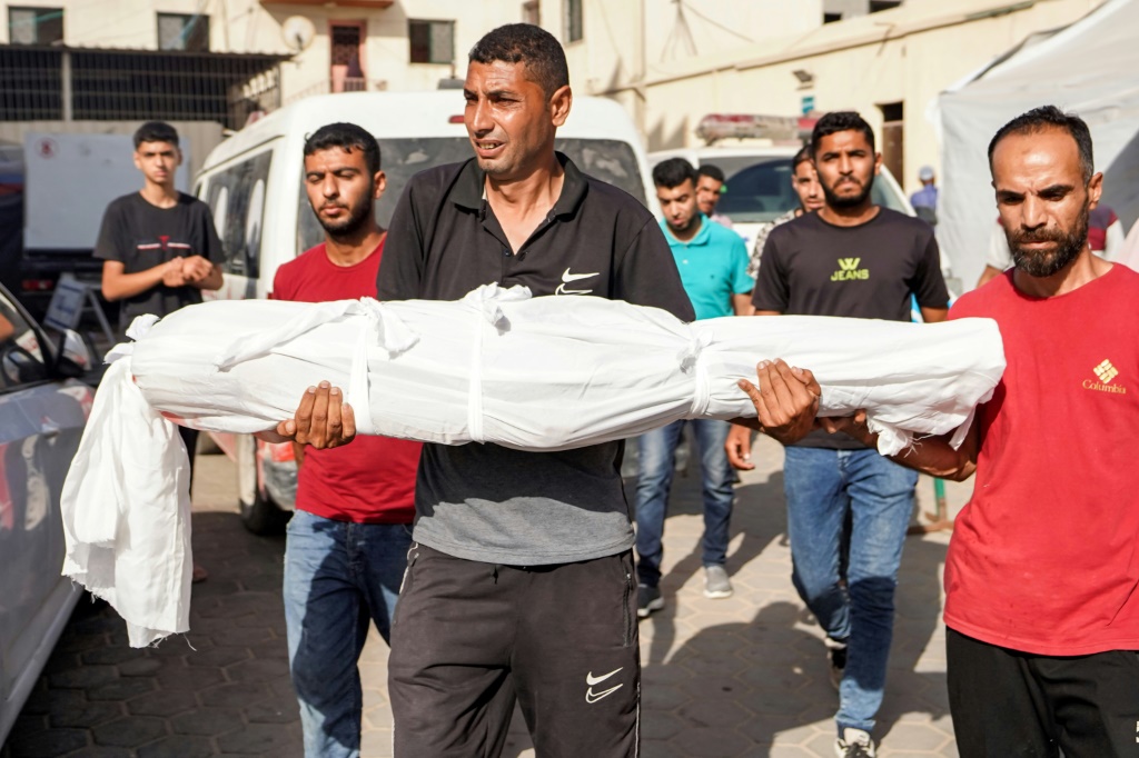    مواطن يحمل جثمان الطفل عبد الرحمن يوسف أبو جلامبو، 11 عاماً، الذي استشهد أثناء القصف الإسرائيلي على مخيم البريج وسط قطاع غزة. (أ ف ب)