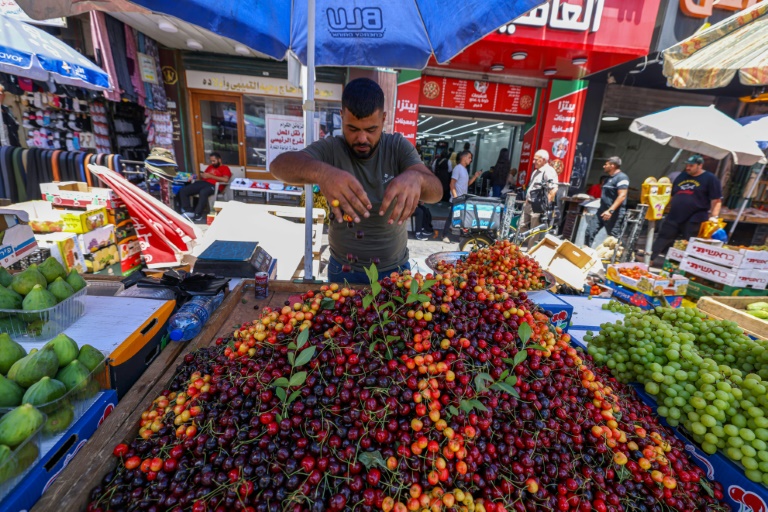 بائع فاكهة فلسطيني يرتّب عربته في سوق رام الله بالضفة الغربية المحتلة في 9 حزيران/يونيو 2024 (أ ف ب)
