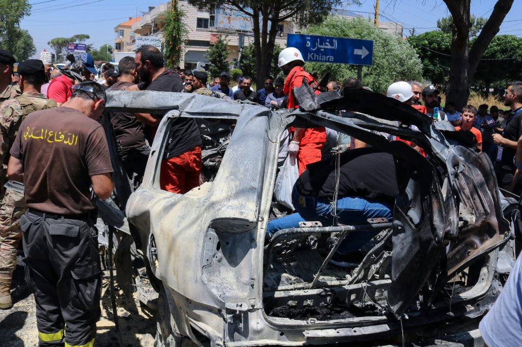   مسعفون ورجال إنقاذ وجنود يتحلقون حول سيارة استهدفتها ضربة اسرائيلية في 22 حزيران/يونيو 2024 في شرق لبنان وأسفرت عن مقتل قيادي من الجماعة الاسلامية المقربة من حركة حماس (أ ف ب)   