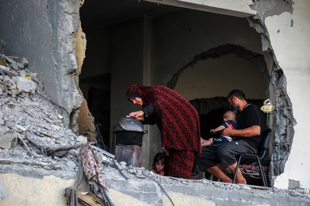    عائلة فلسطينية تتجمع حول موقد حطب مؤقت في مبنى متضرر في خان يونس جنوب غزة (أ ف ب)   
