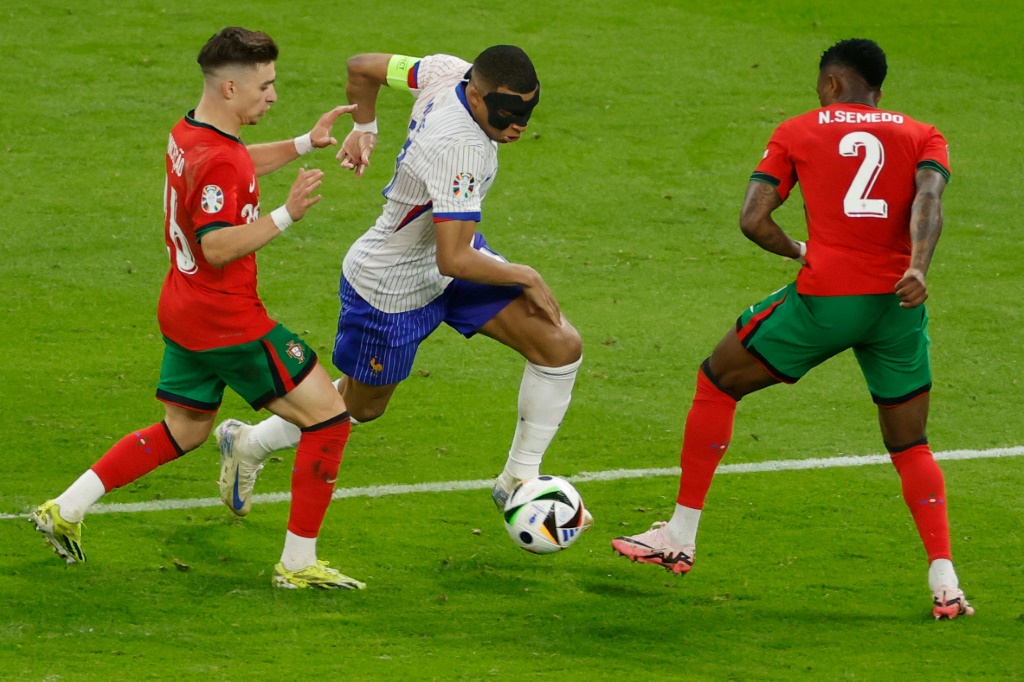 نجم منتخب فرنسا كيليان مبابي (وسط) يحاول اختراق دفاع البرتغال خلال لقاء المنتخبين في كأس اوروبا. 5 تموز/يوليو 2024 (ا ف ب)