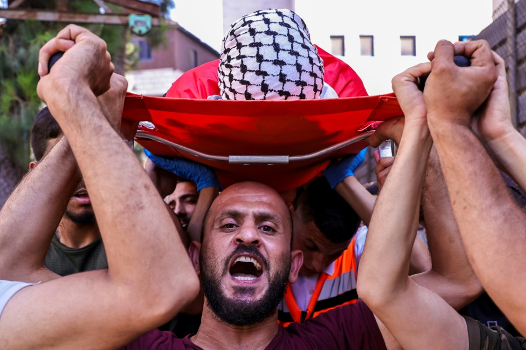 مشيعون يحملون جثمان الطفل غسان غريب (13 عاما) الذي قتل برصاص الجيش الإسرائيلي في قرية دير أبو مشعل بالضفة الغربية المحتلة، خلال جنازته في رام الله في 9 تموز/يوليو 2024 (أ ف ب)   