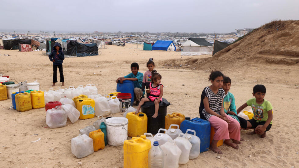 أطفال فلسطينيون نازحون ينتظرون الحصول على الماء في مخيمهم في رفح – تقدر وكالة الأمم المتحدة للطفولة أن الحرب أدت إلى نزوح حوالي 850 ألف طفل في غزة (أ ف ب)