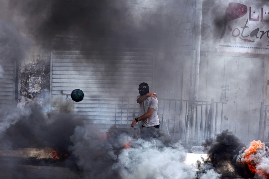 الدخان يتصاعد جراء اشعال شبان فلسطينيون اطارات مركبات خلال المواجهات المندلعة مع القوات الاسرائيلية في مدينة جنين في شمال الضفة الغربية لليوم الثاني على التوالي في 22 أيار/مايو 2024 (أ ف ب)
