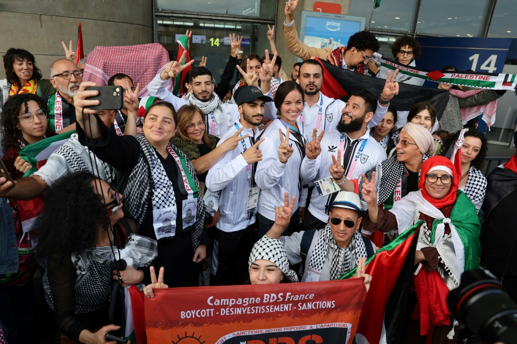 رياضيون فلسطينيون يتوسطون الجماهير المتعاطفة في مطار شارل ديغول في فرنسا. الخميس 25 تموز/يوليو 2024 (ا ف ب)