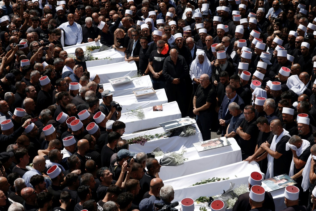مشيعون يحتشدون حول جثامين عشرة من أصل 12 ضحية قضوا في هجوم صاروخي على بلدة مجدل شمس في الجولان السوري الذي تحتله إسرائيل منذ العام 1967، في 28 تموز/يوليو,2024 (أ ف ب)   
