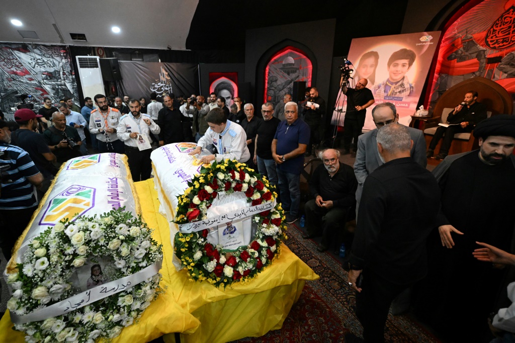 يتجمع الناس حول نعشي الطفلين حسن وأميرة محمد فضل الله خلال جنازتهما في اليوم التالي لمقتلهما في غارة إسرائيلية على مبنى في الضاحية الجنوبية لبيروت. (أ ف ب)   