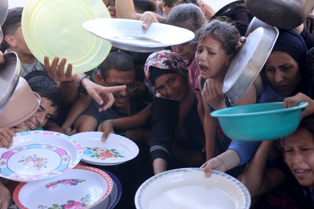 أطفال فلسطينيون يتجمعون في مركز لتوزيع المواد الغذائية في غزة للحصول على وجبة مجانية بتاريخ 18 تموز/يوليو 2024 (أ ف ب)   