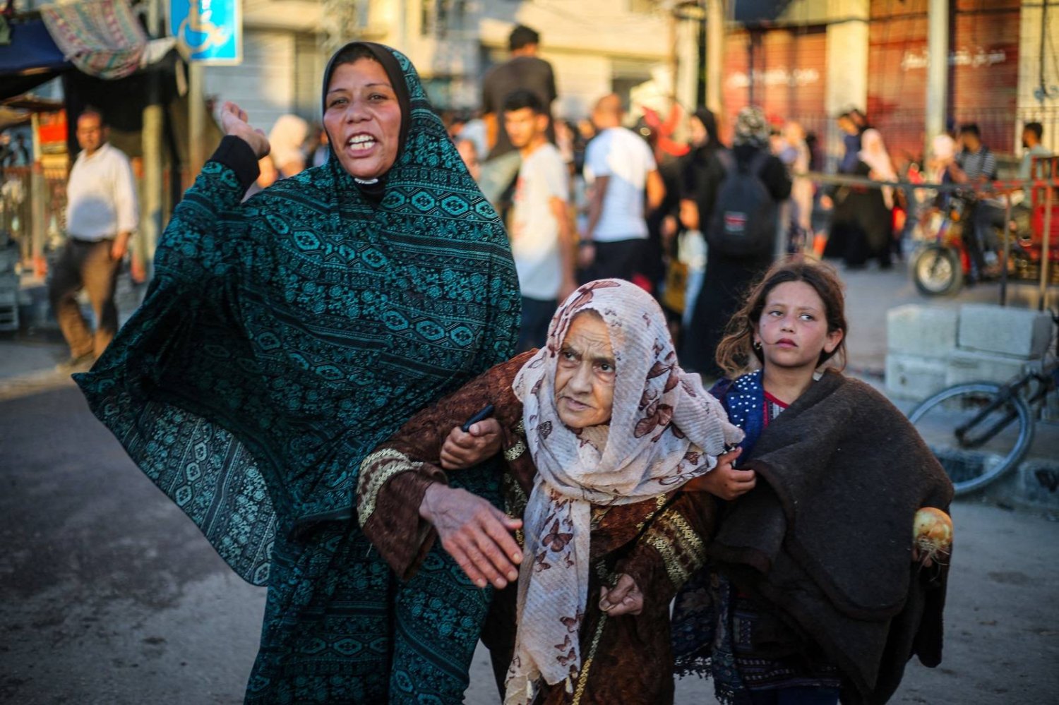 مواطنات فلسطينيات يهربن من مخيم البريج للاجئين وسط قطاع غزة (أ.ف.ب)