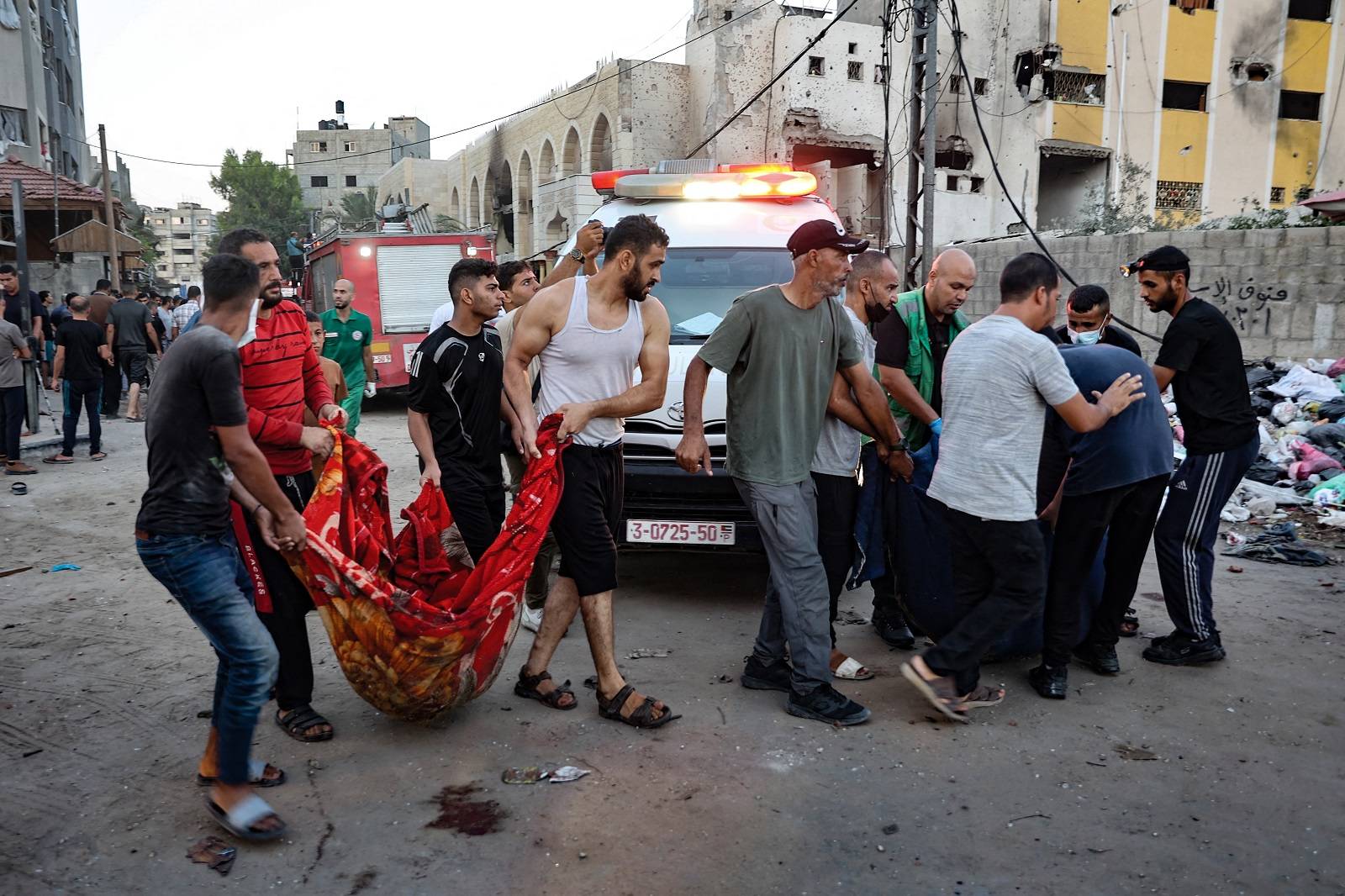 أشخاص ينقلون جثة شخص قُتل في غارة إسرائيلية على مدرسة تؤوي نازحين في غزة (أ.ف.ب)