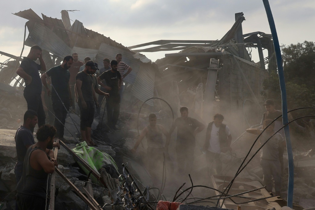 فلسطينيون يتفقدون موقع غارة إسرائيلية في الزوايدة وسط غزة، والتي قالت وكالة الدفاع المدني إنها أسفرت عن مقتل 15 شخصا من عائلة فلسطينية. (أ ف ب)   