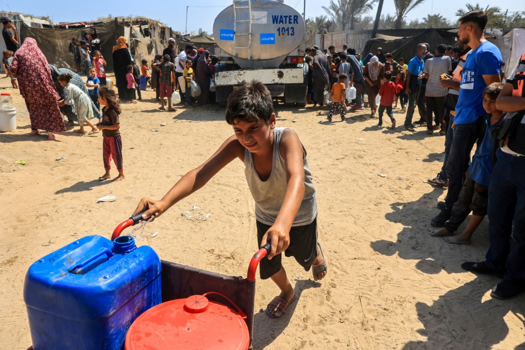 فلسطينيون يحصلون على مياه من شاحنة صهريج تابعة ليونيسف في دير البلج في وسط قطاع غزة في التاسع من تموز/يوليو 2024 (ا ف ب)   