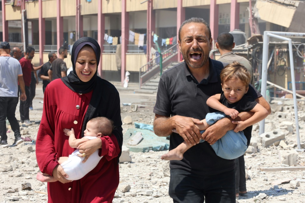   فلسطينيان يحملان طاليهما أثناء فرارهما بعد غارة إسرائيلية على مدرسة تؤوي فلسطينيين نازحين في حي الرمال وسط مدينة غزة في 20 آب/أغسطس 2024 (أ ف ب)   