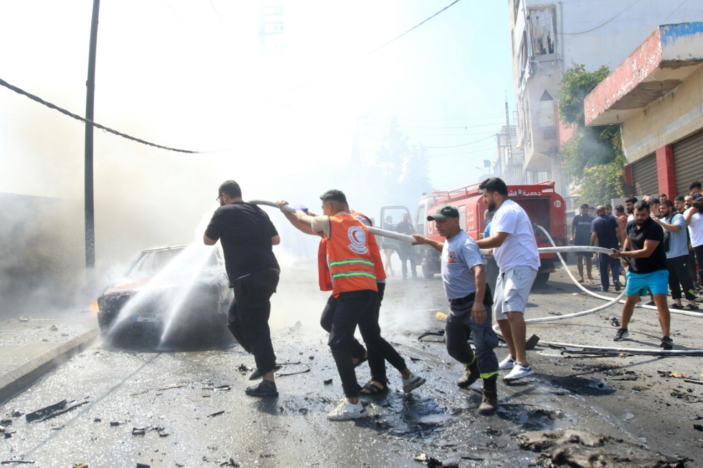 عناصر إطفاء لبنانيون يطفئون سيارة تحترق بعد غارة إسرائيلية على مدينة صيدا بجنوب لبنان أسفرت عن مقتل مسؤول في حركة فتح في 21 آب/آغسطس 2024 (ا ف ب)