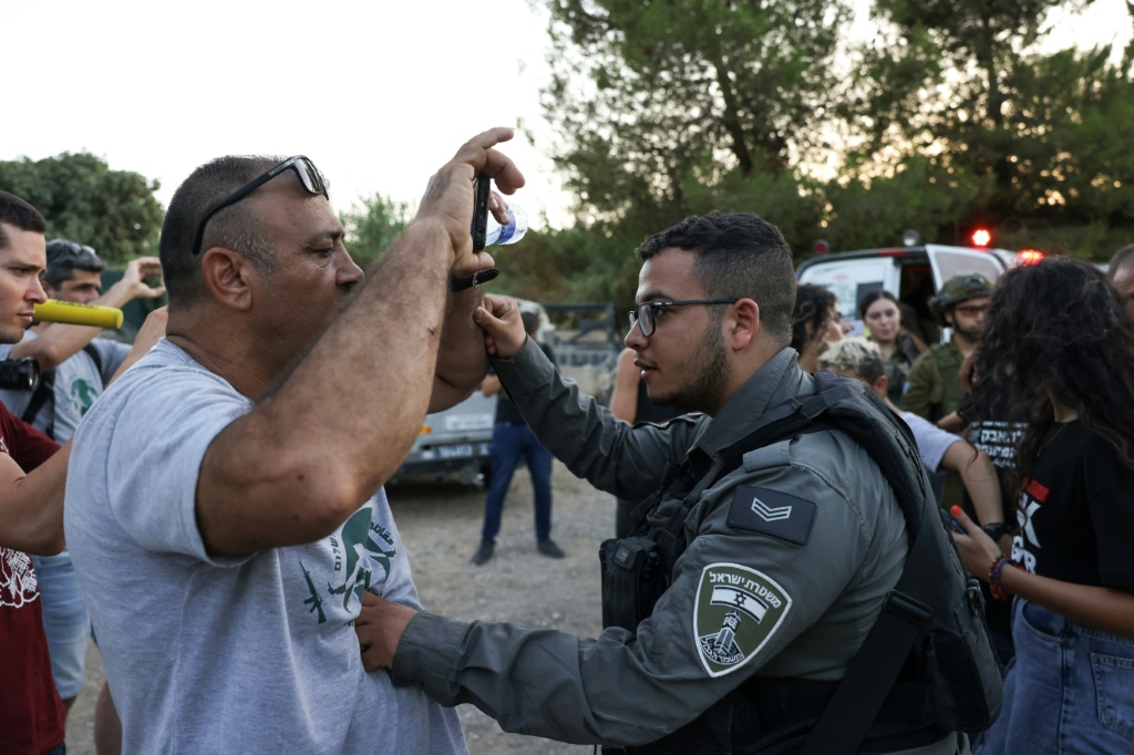 ناشطون يتصدون لمستوطن (يسار) قرب قرية بيت جالا المحتلة بالضفة الغربية (أ ف ب)   