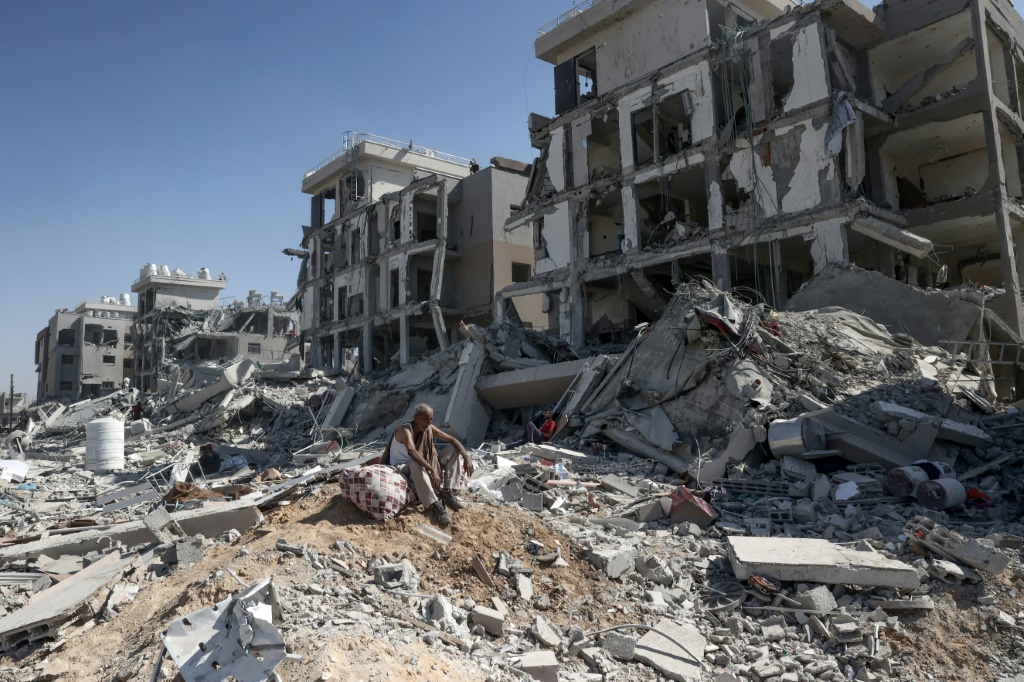 رجل فلسطيني عاد إلى دير البلح في وسط قطاع غزة لتفقد منزله يجلس فوق بعض الأشياء التي تم إنقاذها وسط الدمار (أ ف ب)   