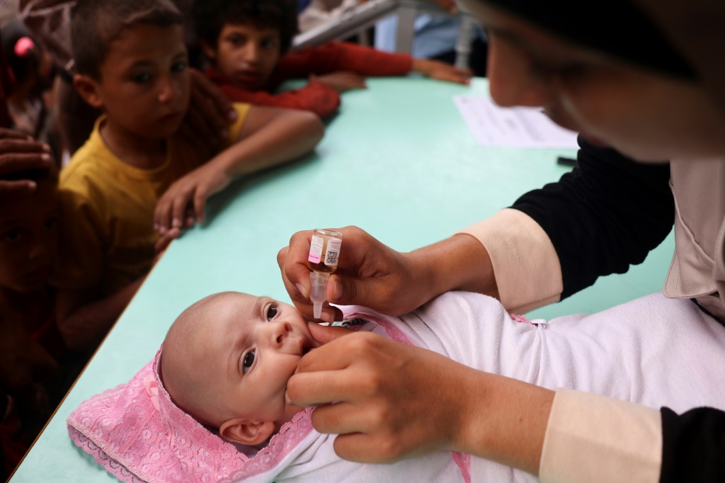 عاملة صحية تعطي لقاح شلل الأطفال لطفلفة في منطقة الزوايدة وسط قطاع غزة في الأول من أيلول/سبتمبر 2024. وقد وفقت إسرائيل وحماس على "هدن إنسانية" لمدة ثلاثة أيام على الأقل لتسهيل حملة التطعيم (أ ف ب)   