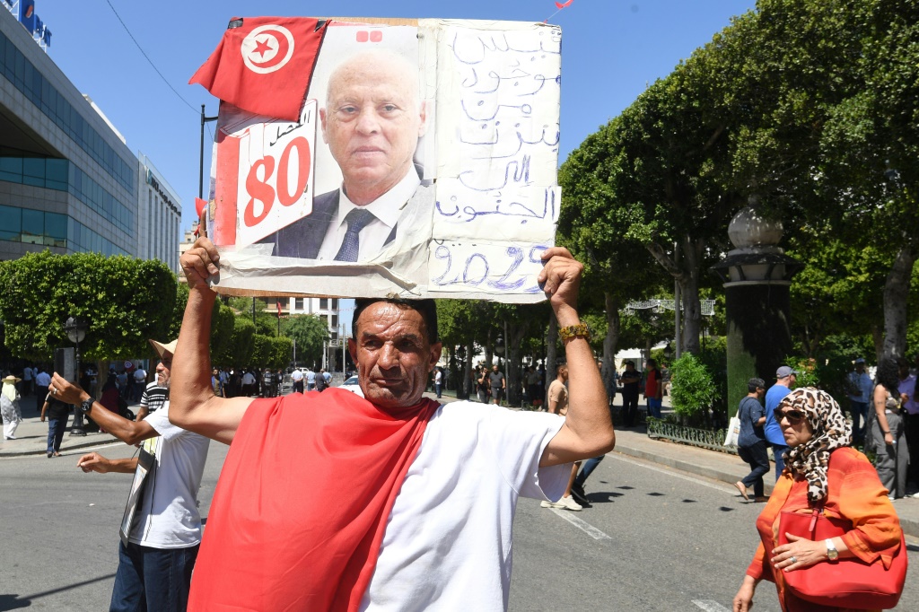 مؤيد للرئيس التونسي قيس سعيّد يرفع صورته خلال تجمع في شارع الحبيب بورقيبة بوسط تونس العاصمة في 25 تموز/يوليو 2024 (أ ف ب)   