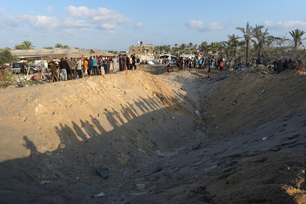 فلسطينيون يقفون على حافة حفرة في مخيم المواصي للنازحين في قطاع غزة (أ ف ب)