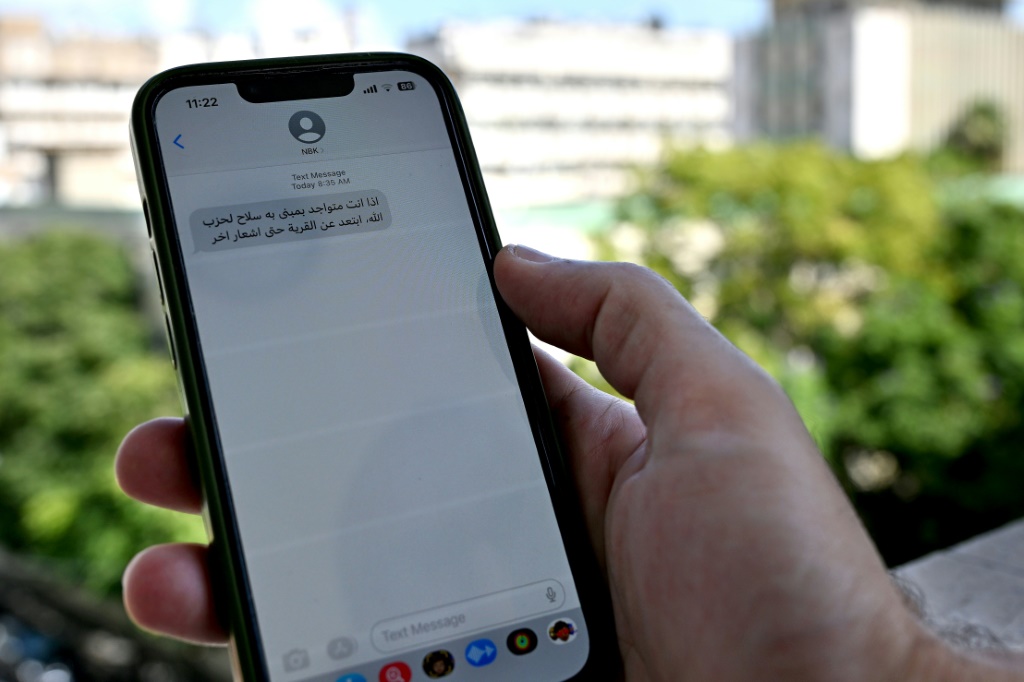 رجل لبناني في بيروت يتفقد رسالة على هاتفه المحمول تدعو الناس إلى إخلاء المناطق التي ينشط فيها حزب الله (أ ف ب)   
