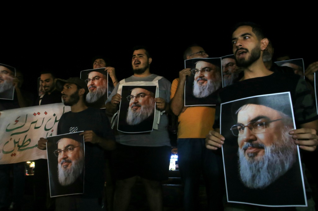 انصار للأمين العام لحزب الله حسن نصرالله يرفعون صورا له في ميجنة صيدا في جنوب لبننا في 28 أيلول/سبتمبر 2024 (أ ف ب)   