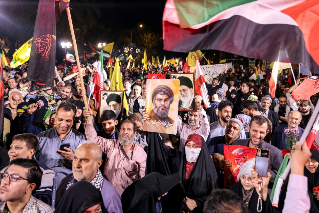 احتفلت حشود من الناس بالضربات الإيرانية يوم الثلاثاء في طهران، وكان بعضهم يحمل صور زعيم حزب الله القتيل حسن نصر الله. (أ ف ب)