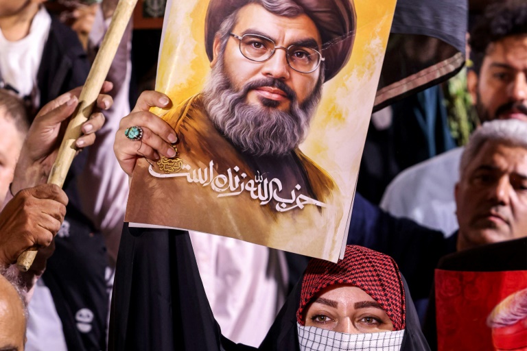امرأة تحمل لافتة عليها رسم للأمين العام لحزب الله اللبناني حسن نصر الله الذي اغتابته إسرائيل في بيروت، مع شعار بالفارسية "حزب الله حيّ"، خلال تجمع للاحتفال بالهجوم الصاروخي الإيراني على إسرائيل خارج مسجد الإمام جعفر الصادق في ساحة فلسطين بطهران في الأول من تشرين الأول/أكتوبر 2024 (ا ف ب)