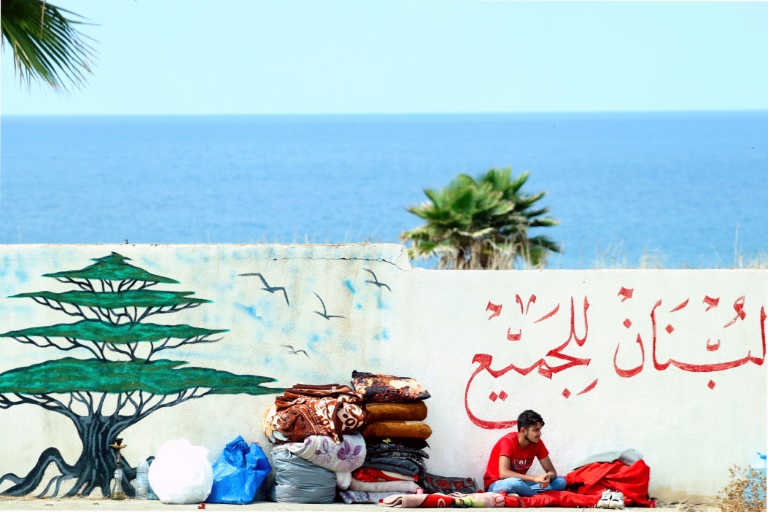 نازح يجلس على الرصيف على واجهة بيروت البحرية في السابع من تشرين الأول/أكتوبر 2024 (أ ف ب)