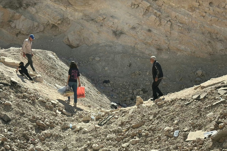أشخاص يفرون من الضربات الإسرائيلية على لبنان يعبرون في حفرة خلفتها غارة إسرئيلية في منطقة المصنع من الجانب اللبناني للمعبر الحدودي الرئيسي مع سوريا في 15 تشرين الأول/أكتوبر 2024 (أ ف ب)