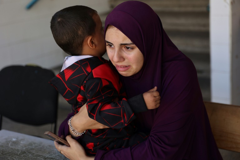 فلسطينية نازحة تحتضن طفلاً داخل مدرسة تابعة للأمم المتحدة تحولت إلى ملجأ في مخيم الشاطئ للاجئين بالقرب من مدينة غزة في شمال قطاع غزة، في أعقاب غارة إسرائيلية في 19 تشرين الأول/أكتوبر 2024 (أ ف ب)