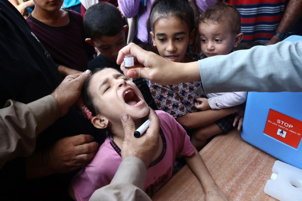 أطفال فلسطينيون يتلقون قطرات ضمن حملة تطعيم ضد شلل الأطفال في دير البلح وسط قطاع غزة (أ ف ب)   