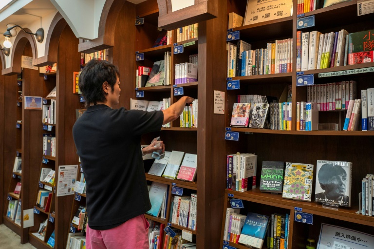 روكورو يوي الذي يملك ثلاث مكتبات لتقاسم الرفوف يرتّب الكتب علة رفوف مكتبته في منطقة كاندا جيمبوتشو بطوكيو في الأول من آب/أغسطس2024(أ ف ب)