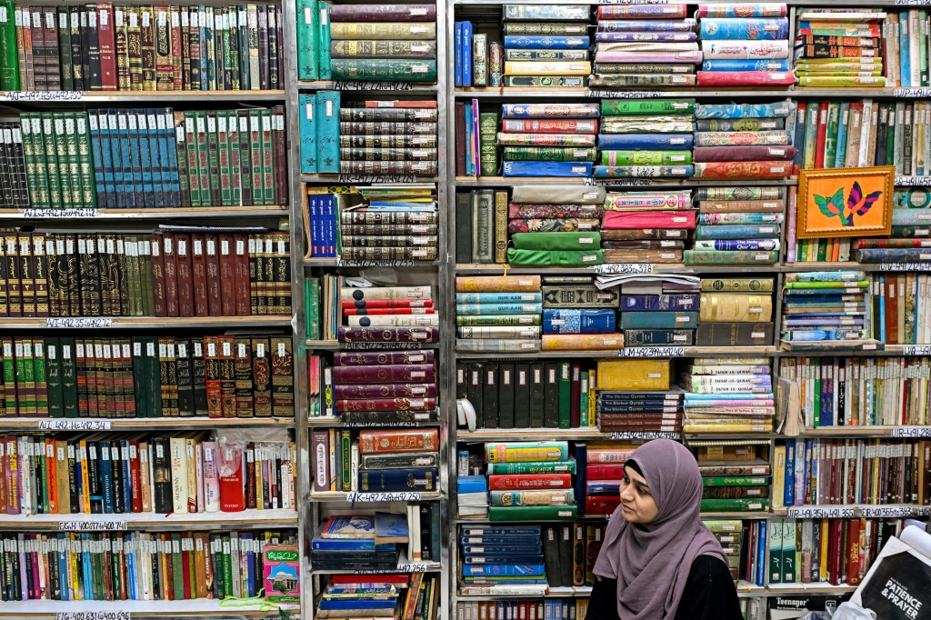   طالب يجلس تحت أرفف مكتظة في مكتبة حضرة شاه ولي الله العامة (أ ف ب)  