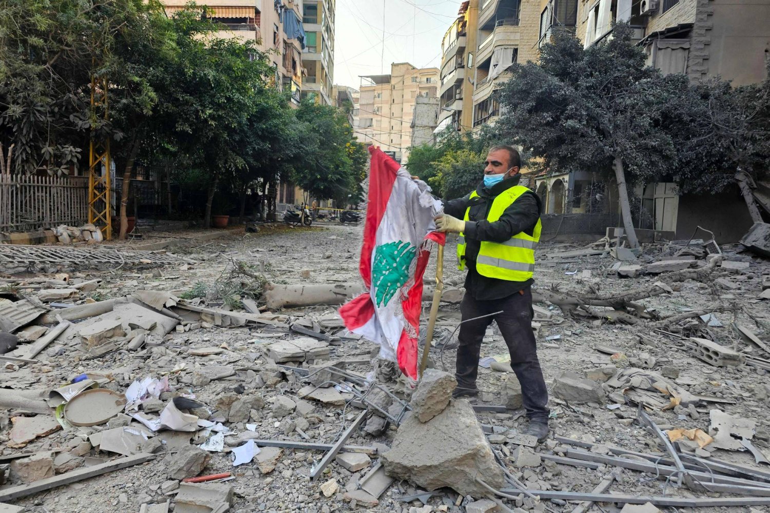 أحد عمال البلدية ينتشل العلم اللبناني من بين الأنقاض في حارة حريك بالضاحية الجنوبية لبيروت (أ.ف.ب)