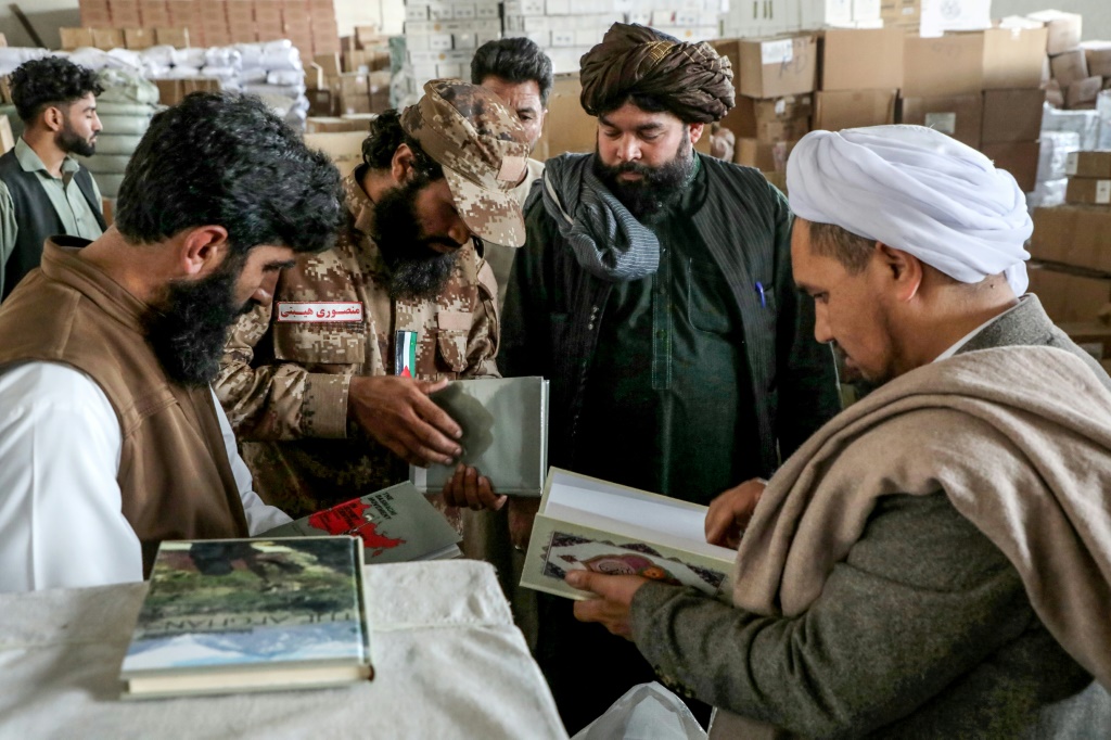 موظفو حكومة طالبان يقيمون الكتب المستوردة من إيران إلى أفغانستان في مستودع جمركي في هرات (أ ف ب)   