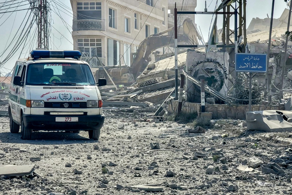 سيارة إسعاف تمر بين أنقاض مبنى مدمر بعد غارة جوية إسرائيلية على قرية كفر تبنيت في جنوب لبنان في 14 تشرين الأول/أكتوبر 2024 (أ ف ب)   