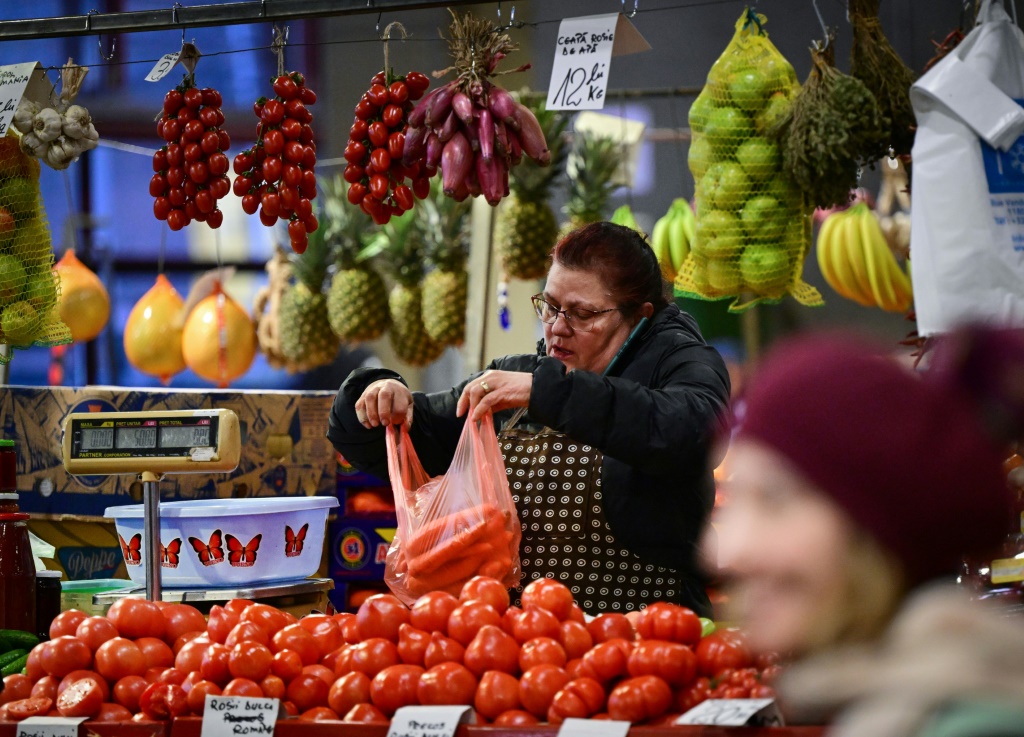 بائع يملأ كيسًا بالجزر في سوق بياتا أوبور في بوخارست (أ ف ب)   