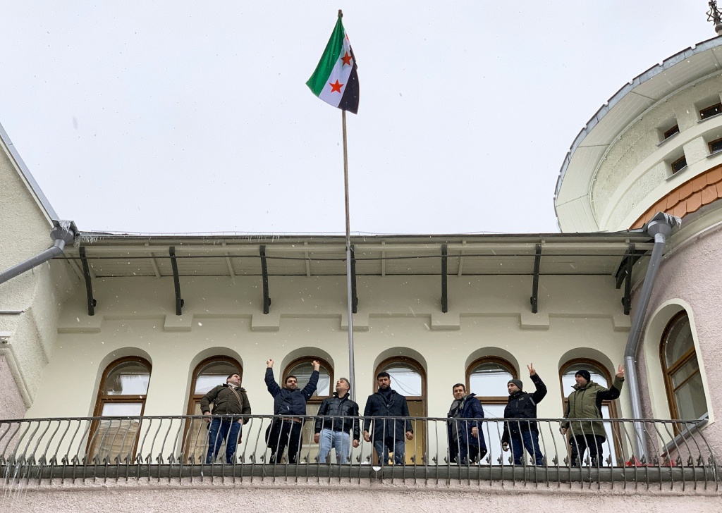 متظاهرون مبتهجون بعد رفع علم المعارضة السورية على السفارة السورية في موسكو في 9 كانون الأول/ديسمبر 2024 (أ ف ب)   