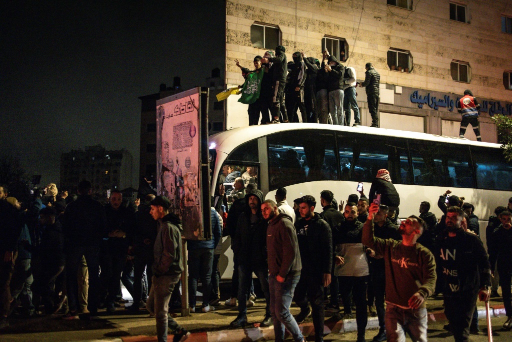 فلسطينيون يستقبلون حافلة تقل فلسطينيين كانوا معتقلين في سجون إسرائيلية في بيتونيا في الضفة الغربية المحتلة في 20 كانون الثاني/يناير 2025 (أ ف ب)   