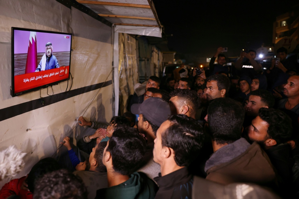 فلسطينيون في شارع بخان يونس في جنوب قطاع غزة يشاهدون في 15 كانون الثاني/يناير 2025 يشاهدون البث المباشر للمؤتمر الصحافي الذي عقده رئيس الوزراء القطري الشيخ محمد بن عبد الرحمن بن جاسم آل ثاني (أ ف ب)   