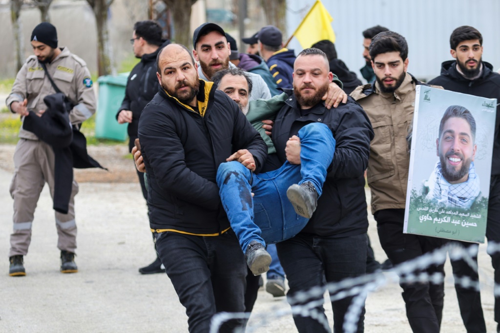 أشخاص يحملون جريحا أصيب بنيران إسرائيلية في بلدة برج الملوك بجنوب لبنان في 26 كانون الثاني/يناير 2025 (ا ف ب)   