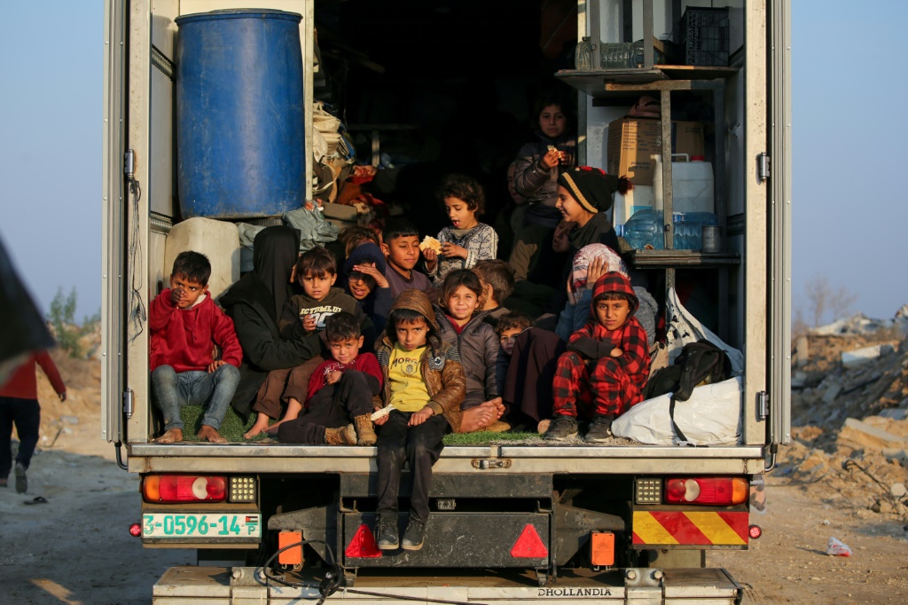 أطفال فلسطينيون نازحون يجلسون في مؤخرة شاحنة أثناء العودة من جنوب قطاع غزة إلى شماله في 29 كانون الثاني/يناير 2025 (أ ف ب)