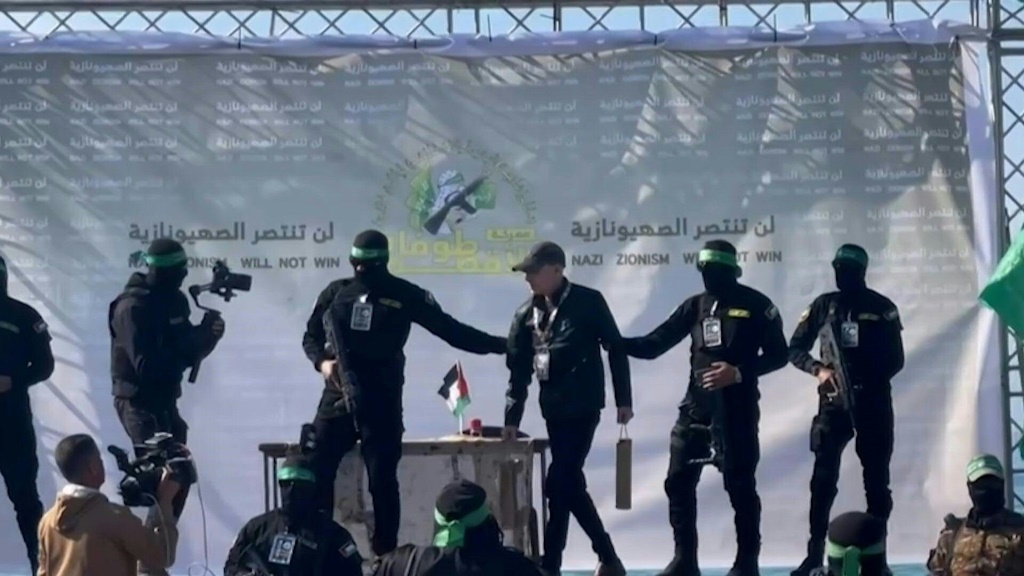 الرهينة الأميركي الإسرائيلي كيث سيغل بين عنصرين من حركة حماس خلال تسليمه الى الصليب الأحمر في مدينة غزة في الأول من شباط/فبراير 2025 (أ ف ب)   
