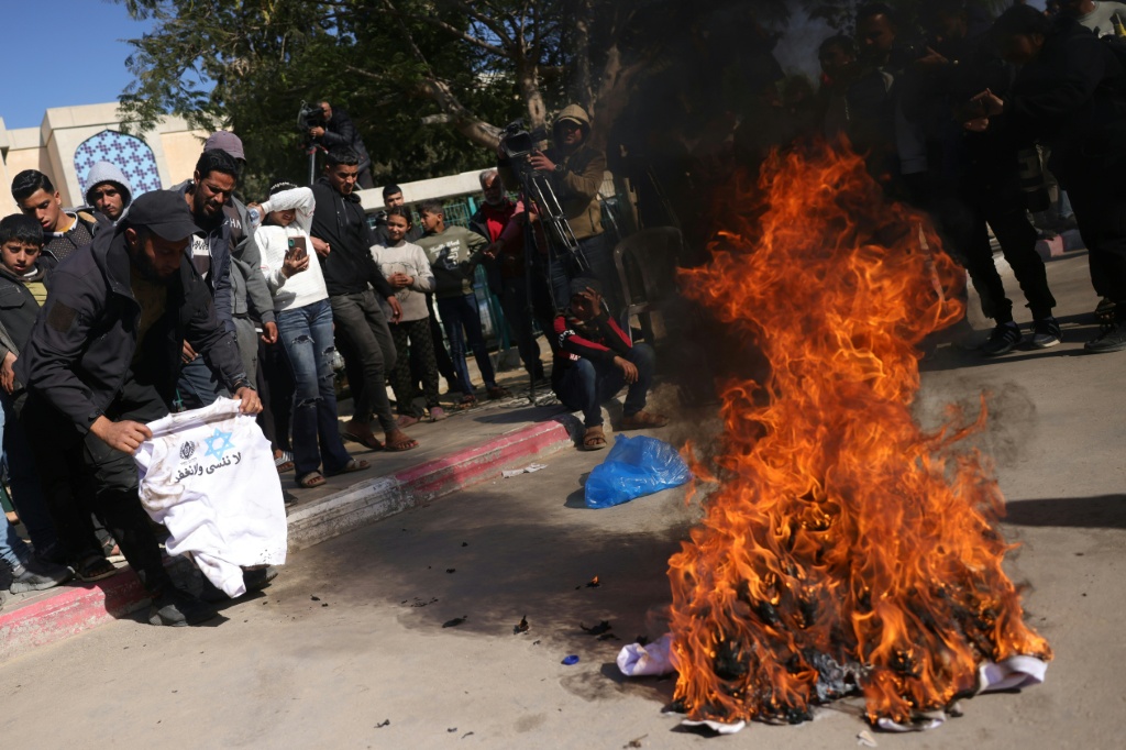 فلسطيني يستعد لحرق سترة عليها شعار مصلحة السجون ونجمة داود وعبارة "لا ننسى ولا نغفر" تم توزيعها على المعتقلين الفلسطينيين المحررين أمام المستشفى الأوروبي بخان يونس جنوب قطاع غزة في 15 شباط/فبراير 2025 (أ ف ب)   