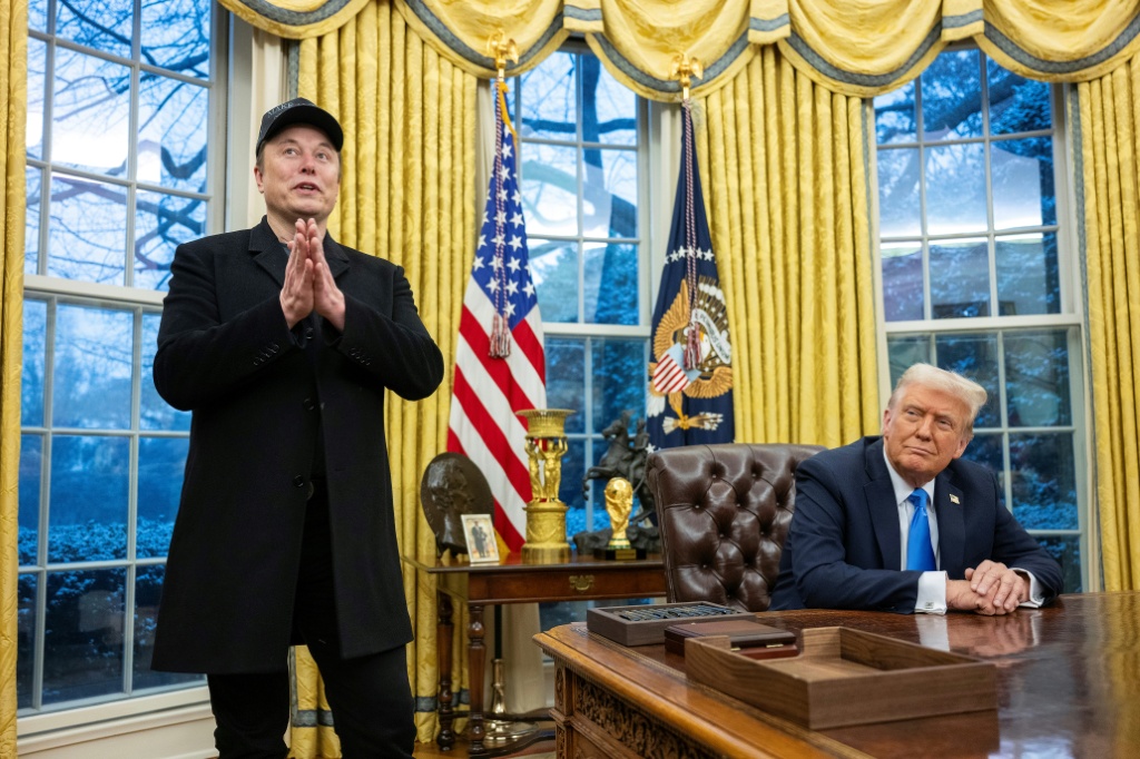 الرئيس الأميركي دونالد ترامب جالسا الى مكتبه في البيت الأبيض والى جانبه إيلون ماسك في 11 شباط/فبراير 2025 (أ ف ب)   