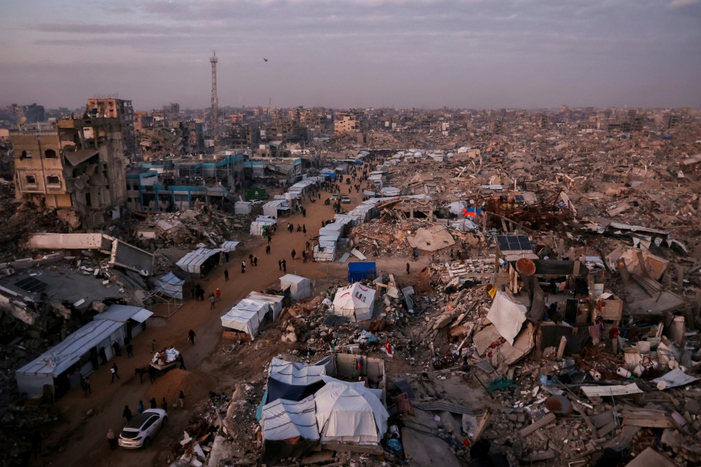    فلسطينيون يسيرون بالقرب من خيام أقيمت وسط أنقاض مبان مدمرة، بتاريخ 18 شباط/فبراير 2025 في جباليا في قطاع غزة (أ ف ب)   