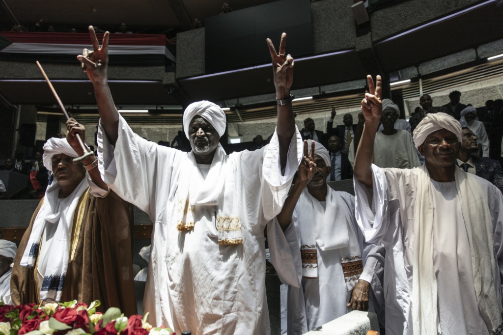 مندوبو ولاية غرب دارفور بالسودان يغنون ويهتفون قبل التوقيع على ميثاق حكومة السلام والوحدة في مركز كينياتا الدولي للمؤتمرات في نيروبي في 18 شباط/فبراير 2025 (أ ف ب)   