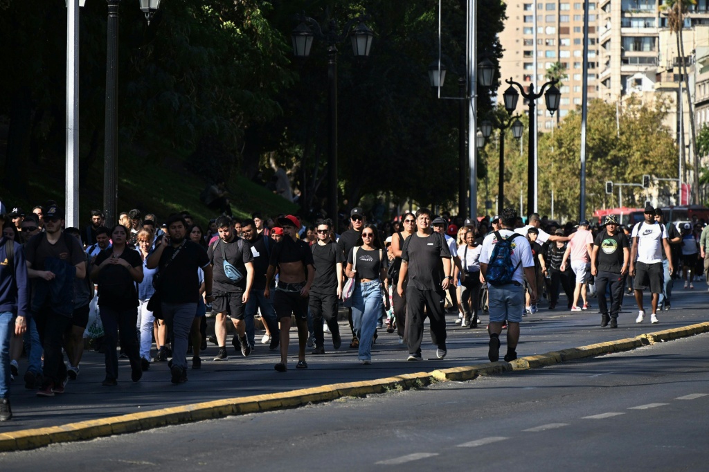 أناس يسيرون في منتصف شارع ألاميدا في سانتياغو إثر انقطاع التيار الكهربائي عن معظم أنحاء تشيلي في 25 شباط/فبراير 2025. (أ ف ب)   