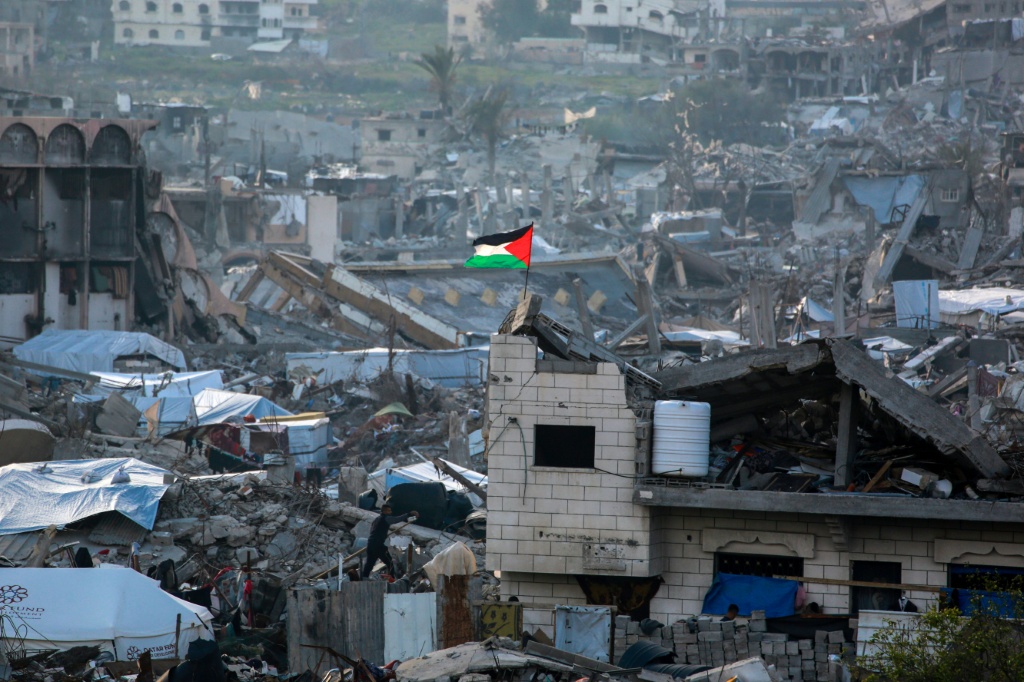 علم فلسطيني يرفرف وسط أنقاض المباني في بيت لاهيا شمال قطاع غزة في 4 آذار/مارس 2025 (أ ف ب)   